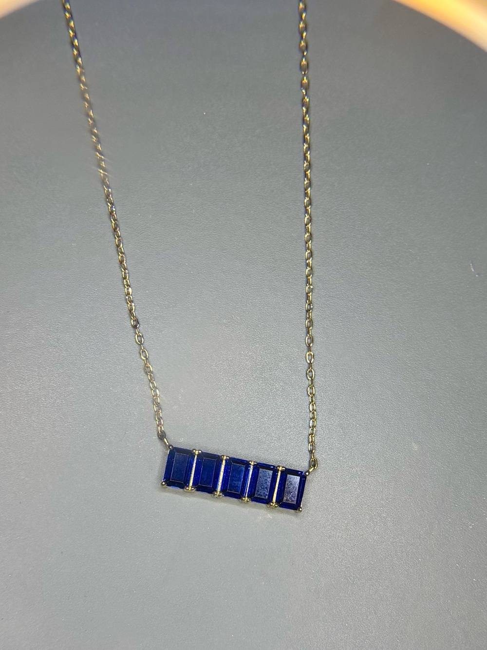 gold tone necklace with blue crystal bar